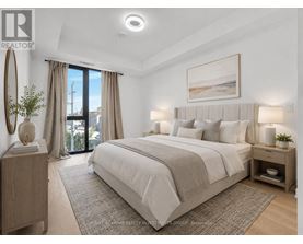 A bedroom with a large bed, a nightstand with a lamp, and a framed picture on the wall.