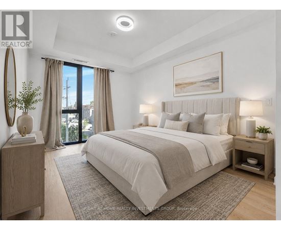A bedroom with a large bed, a nightstand with a lamp, and a framed picture on the wall.