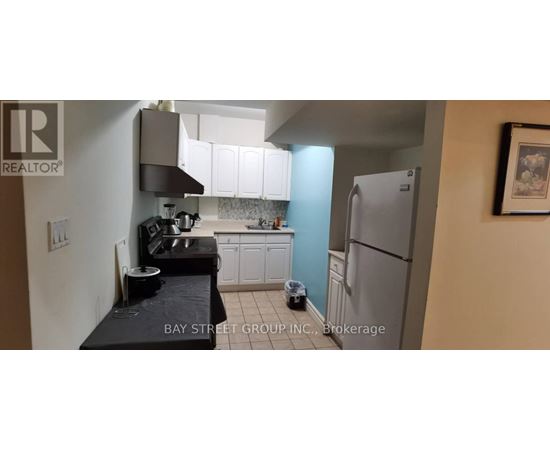 A kitchen with a refrigerator, sink, and cabinets.