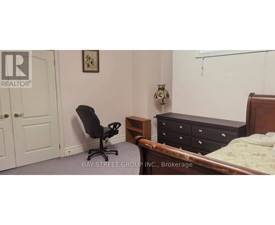 A bedroom with a bed, nightstand, chair, and lamp.