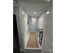 A hallway with a rug on the floor and a door at the end.