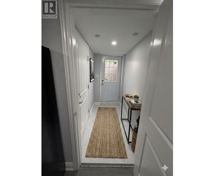 A hallway with a rug on the floor and a door at the end.