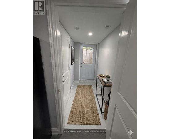 A hallway with a rug on the floor and a door at the end.