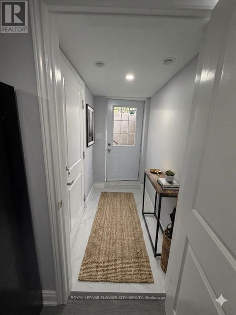 A hallway with a rug on the floor and a door at the end.