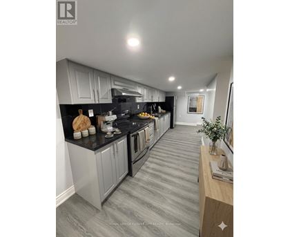 A modern kitchen with grey cabinets and black countertops.