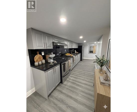 A modern kitchen with grey cabinets and black countertops.