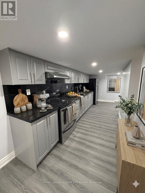 A modern kitchen with grey cabinets and black countertops.