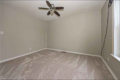 A room with a ceiling fan and carpeted floor.
