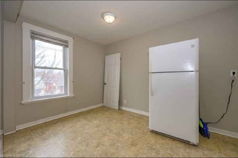 A white refrigerator sits in a room with a window and a door.