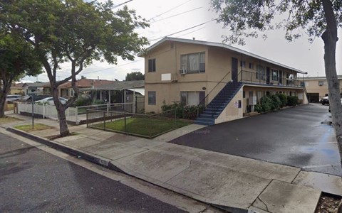 A residential building with a driveway and a tree in front.