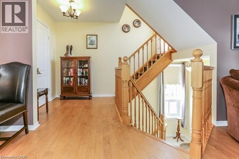 A living room with a brown leather chair and a wooden staircase.