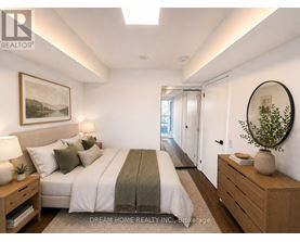 A well-lit bedroom with a large bed and a side table with a lamp.