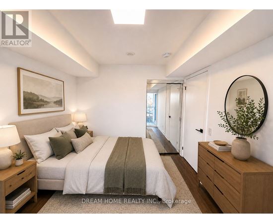 A well-lit bedroom with a large bed and a side table with a lamp.
