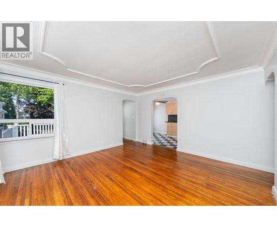 A room with wooden floors and white walls, with a window on the left side.