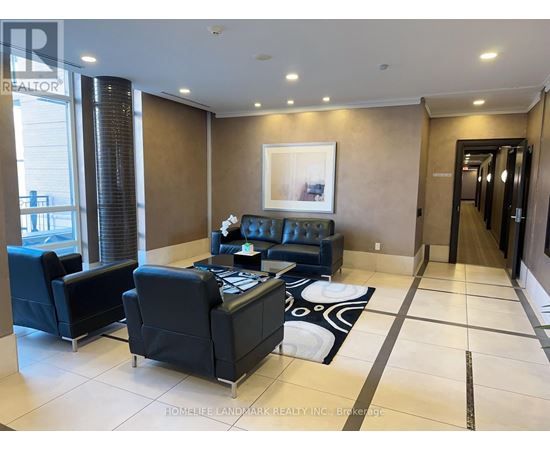 A living room with a black couch and a painting on the wall.