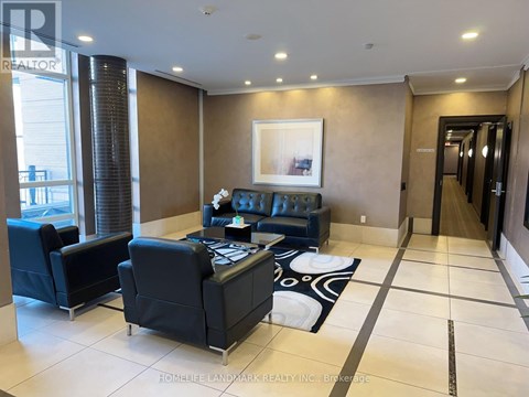 A living room with a black couch and a painting on the wall.