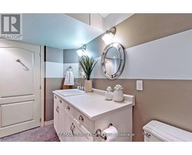A bathroom with a white sink and a round mirror.