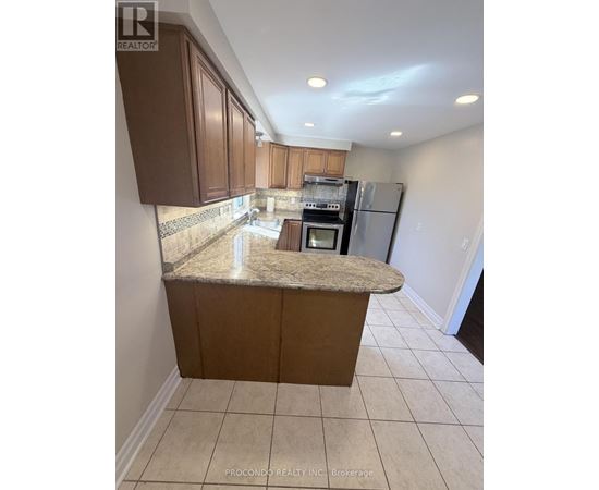 A kitchen with brown cabinets and a granite countertop.