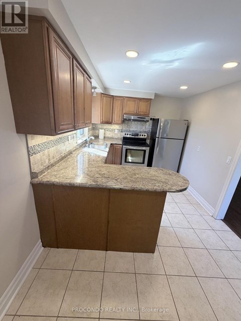 A kitchen with brown cabinets and a granite countertop.