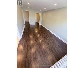 A room with wooden flooring and white walls.