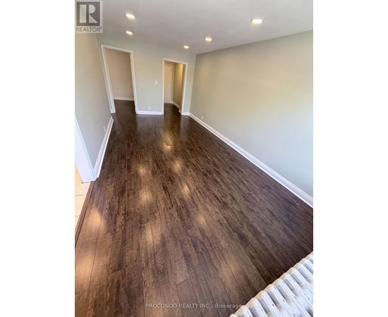 A room with wooden flooring and white walls.