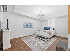 A bedroom with a white bed and a colorful rug.
