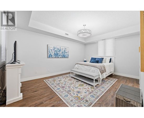 A bedroom with a white bed and a colorful rug.
