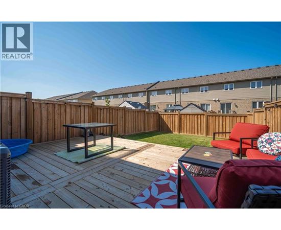 A wooden deck with a table and chairs is in front of a building.