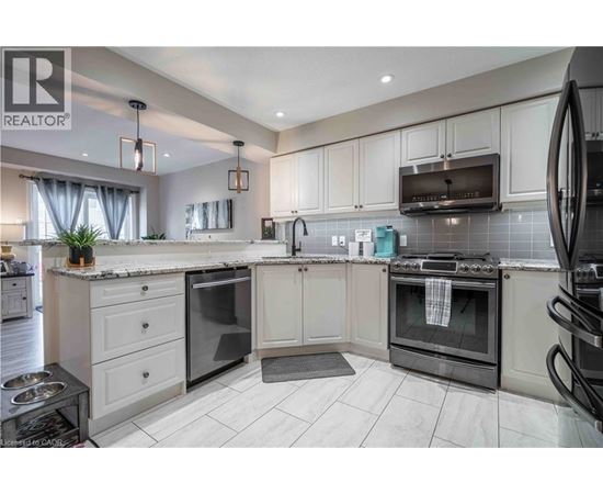 A modern kitchen with white cabinets and black appliances.
