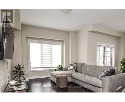 A living room with a grey couch, a black and white pillow, a black television and a black coffee table.