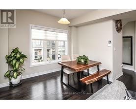 A dining room with a wooden table and bench, a potted plant, and a window showing an apartment building outside.