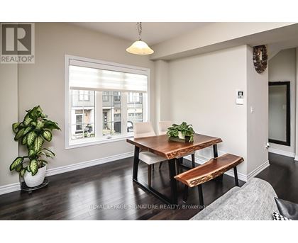 A dining room with a wooden table and bench, a potted plant, and a window showing an apartment building outside.
