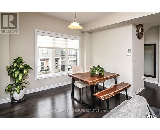 A dining room with a wooden table and bench, a potted plant, and a window showing an apartment building outside.