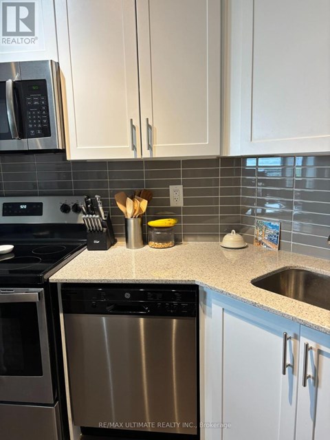 A kitchen with a stainless steel dishwasher and white cabinets.