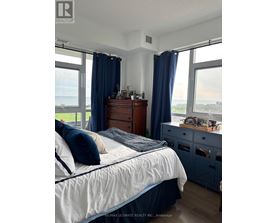 A bedroom with a bed, dresser, and window with blue curtains.