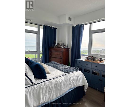 A bedroom with a bed, dresser, and window with blue curtains.