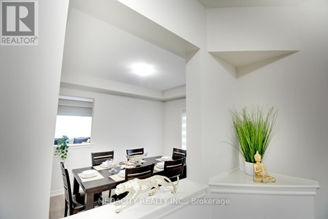 A dining room with a table set for two and a plant on the side table.