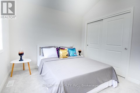 A bedroom with a bed, a small table with a vase and a pillow on it, and a door.