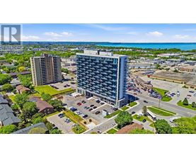 A bird's eye view of a city with two tall buildings, a parking lot, and a road with cars.