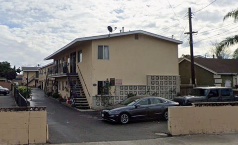 A car is parked in front of a house with a staircase leading to the front door.