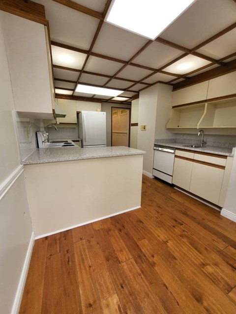 A kitchen with white cabinets and wooden floors.