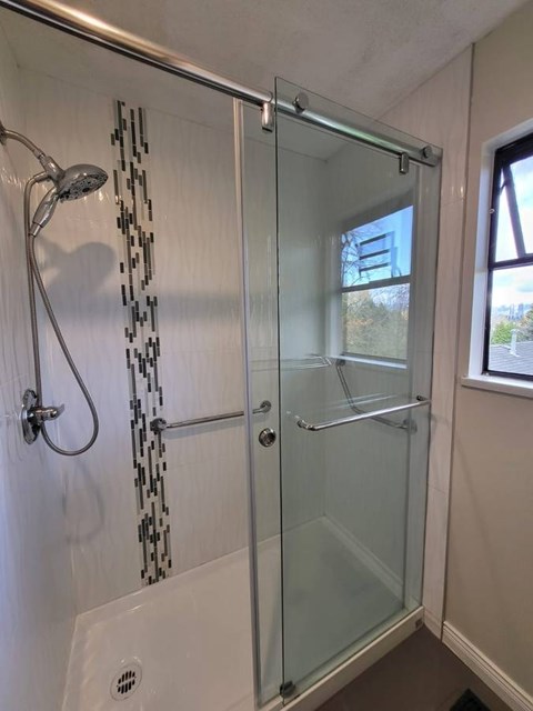 A shower with a glass door and a glass shower head.