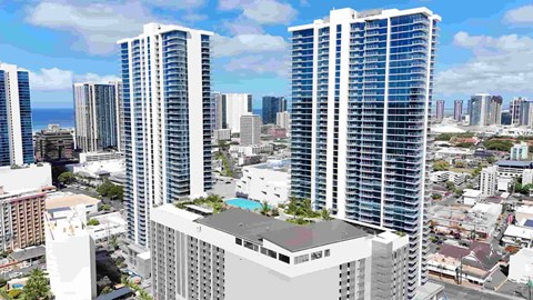 Two tall buildings with a pool on the roof in the middle of a city.