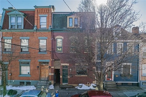 A red brick building with a tree in front of it.