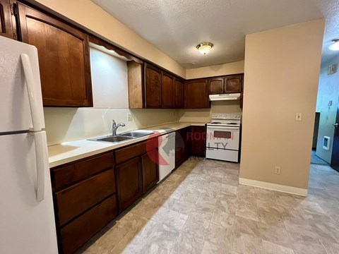 A kitchen with a white fridge and brown cabinets.