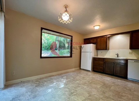 A kitchen with a refrigerator, sink, and cabinets.
