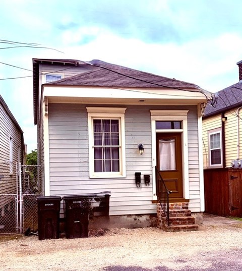 A small house with a grey siding and a brown door.
