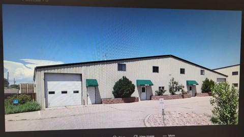 A large industrial building with a white garage door and green awnings.