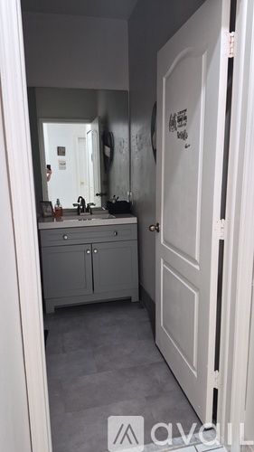 A bathroom with a white door and a mirror on the wall.