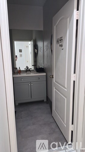 A bathroom with a white door and a mirror on the wall.